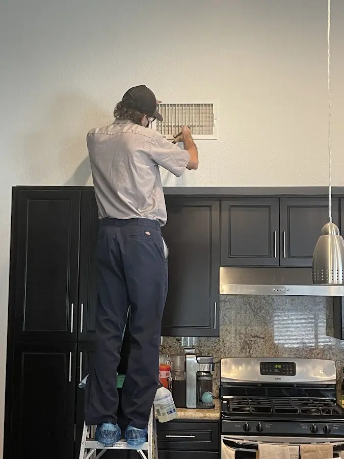 Technician inspecting an air vent during HVAC service in Hamilton
